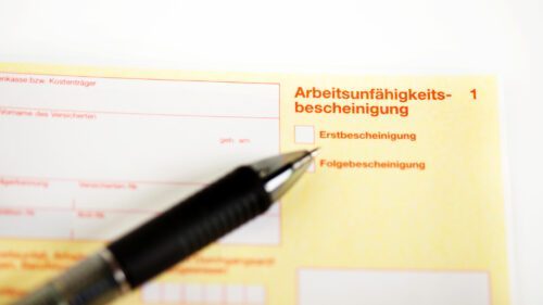 Eine Arbeitsunfähigkeitsbescheinigung mit einem darauf liegenden Stift.